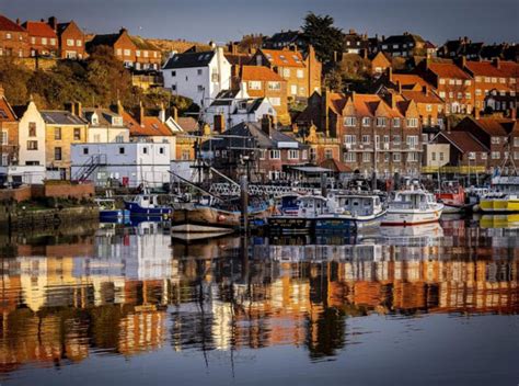 the boats are docked in the harbor by the houses on the hill behind ...