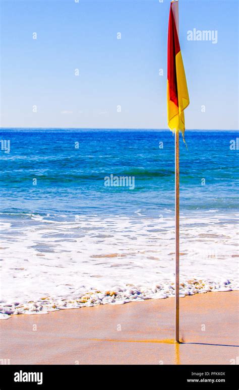 red and yellow beach flag on a beach Stock Photo - Alamy