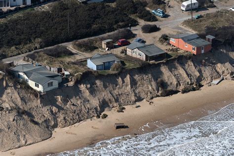 an aerial view of houses on the edge of a cliff next to the beach and ocean