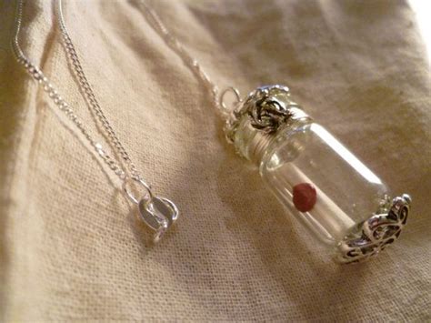 A small glass vial necklace with silver plated accents with a tiny ...