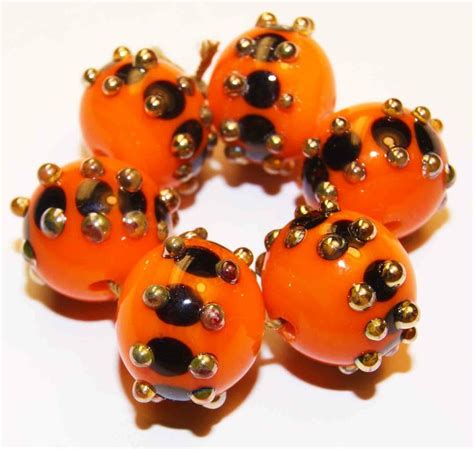 five orange beads with black and gold accents on them are sitting in a circle together