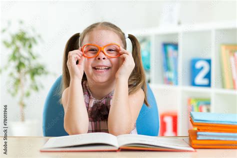 Cute little girl reading a book while wearing glasses Stock Photo | Adobe Stock