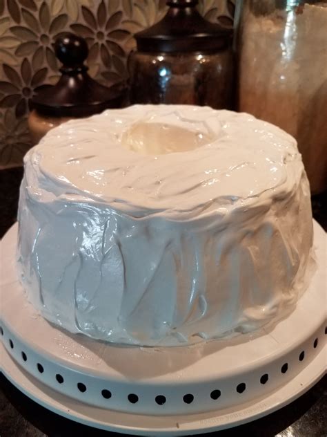 a white frosted cake sitting on top of a counter next to a glass jar