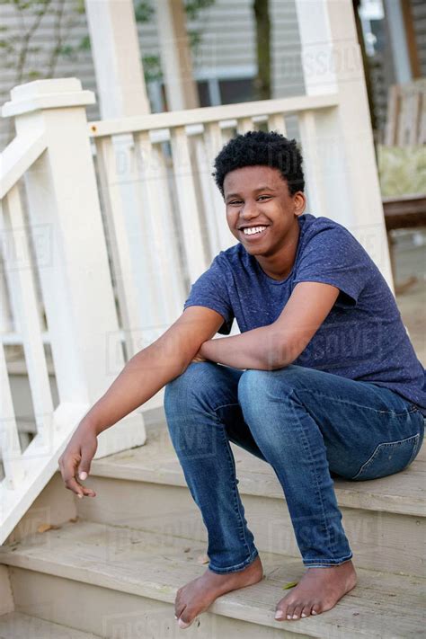 Portrait confident, carefree barefoot teenage boy on front stoop - Stock Photo - Dissolve