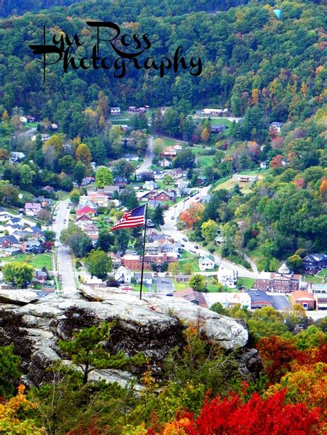 a flag on top of a rock overlooking a small town in the distance with ...