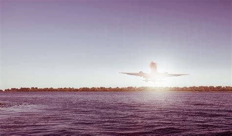 Premium Photo | A plane is taking off over the water.