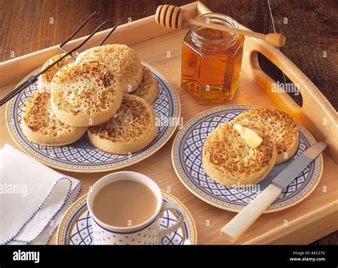 A teatime tray of english crumpets honey and tea on a wooden tray editorial food Stock Photo - Alamy