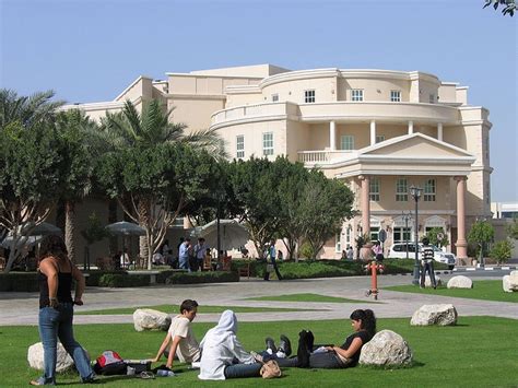 people sitting on the grass in front of a building