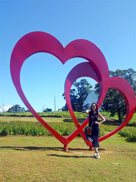 a woman standing in front of two large heart shaped metal sculptures on ...