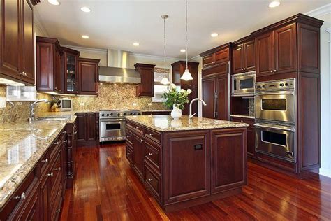 Kitchen in luxury home with dark cherry wood cabinetry, wood flooring ...