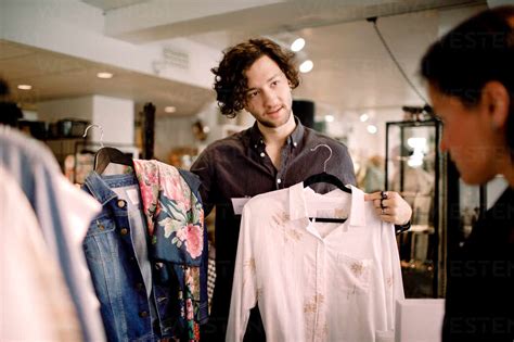 Salesman showing clothes to customer at store stock photo