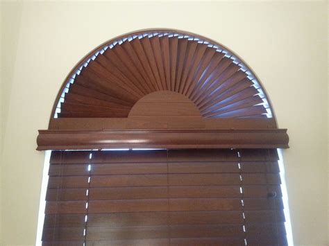 an arched window with wooden blinds in the corner and sunburst on it's side