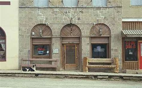 a dog laying on the ground in front of a building with arched windows and doors