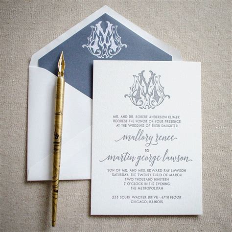 the wedding stationery is laid out on top of an envelope with a pen next to it