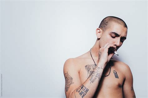 "Tattooed Young Man Smokes A Cigarrette Over White Wall" by Stocksy Contributor "Ohlamour Studio ...