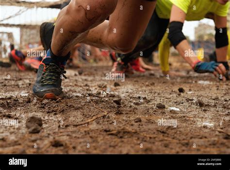 Mud race runners. Crawling,passing under a barbed wire obstacles during ...