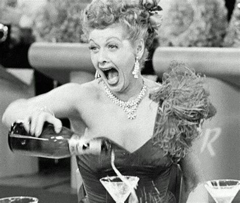 a woman in a dress pouring drinks at a table with two martini glasses on it