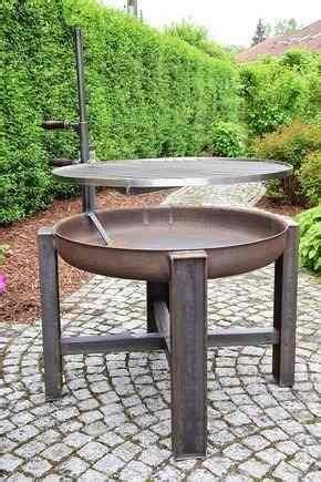 a metal table sitting on top of a brick walkway next to a lush green hedge