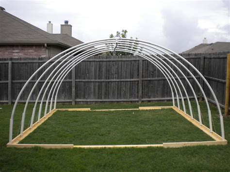 a backyard area with an arch and grass in the foreground, next to a fence