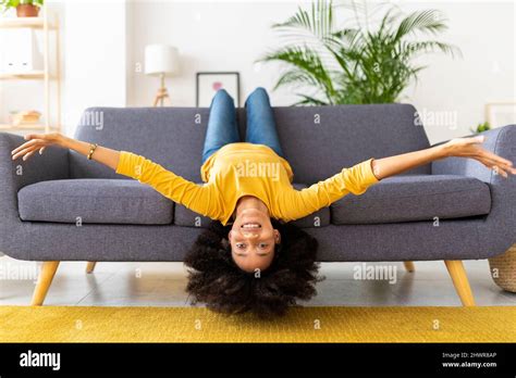 Happy young woman lying upside down on sofa in living room at home Stock Photo - Alamy