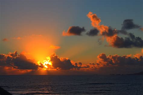 the sun is setting over the ocean with clouds