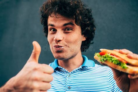 Portrait of Happy Handsome Young Man Eating a Healthy Burger Showing Thumb Up. Hungry Man in a ...