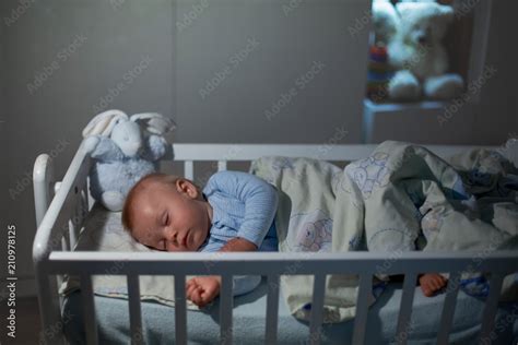 Adorable newborn baby boy, sleeping in crib at night. Little boy in ...