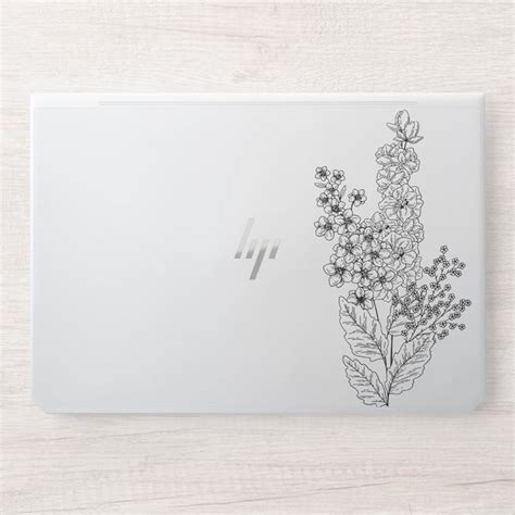 an hp laptop with flowers and leaves on the back cover sitting on a ...