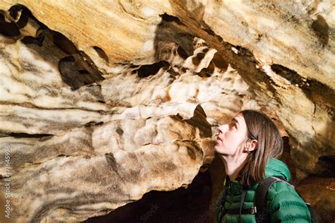 Speleologist male examining sandstone cave interior with growing pink marble clusters Stock ...