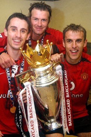 three men in red shirts holding up a trophy