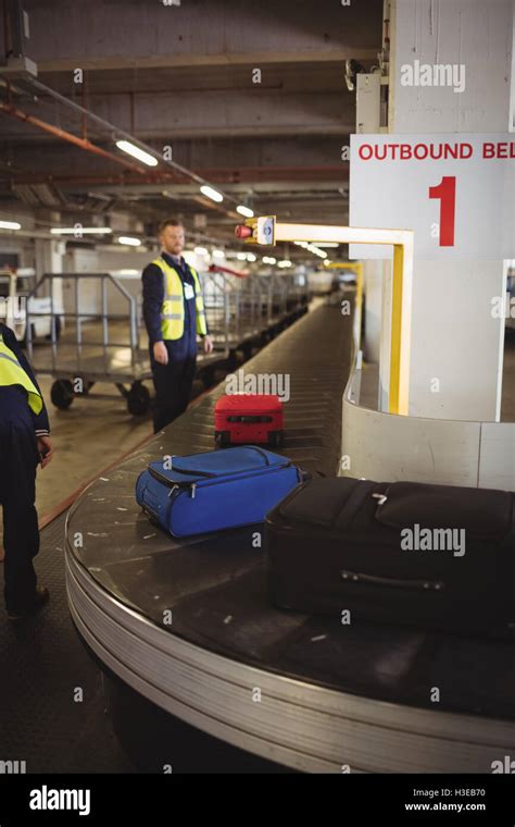 Airport ground crew unloading luggage from baggage carousel Stock Photo - Alamy