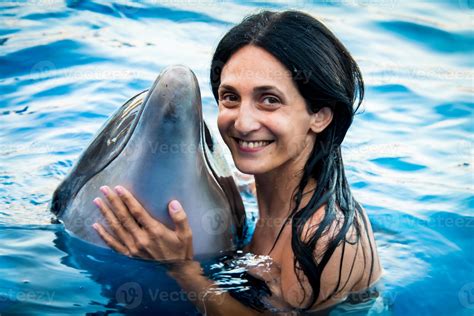 Portrait of young Caucasian woman smile with dolphin look to camera in pool water of Batumi ...