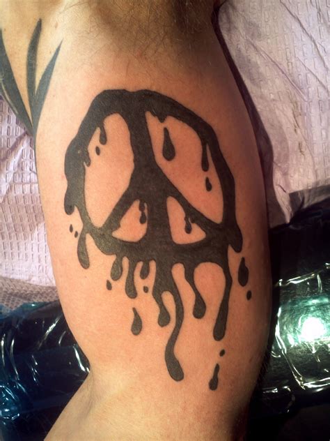 a man with a peace sign tattoo on his arm and shoulder is covered in black ink