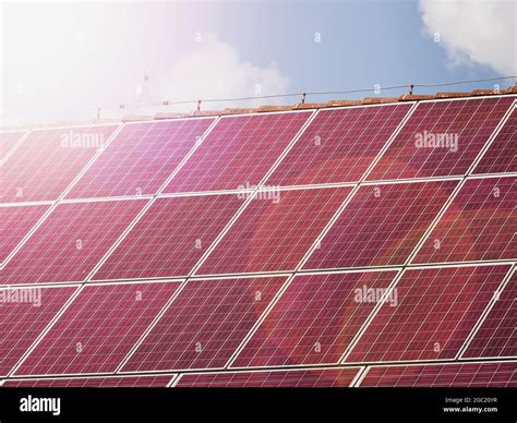 Red solar panels on house roof, renewable energy concept. Hot sun reflection in photovoltaic ...