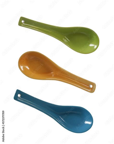 Three different colour porcelain spoons with hanging holes isolated on transparent background ...