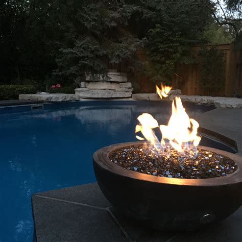 Fire and water -- black concrete fire bowl with crushed black glass sparkles over the sereni ...