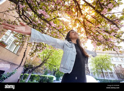 Young girl with arms wide open and enjoying in sunshine standing outdoor in sun light on the ...