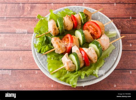 Traditional chicken kebab on wooden skewers with tomatoes, cucumbers ...