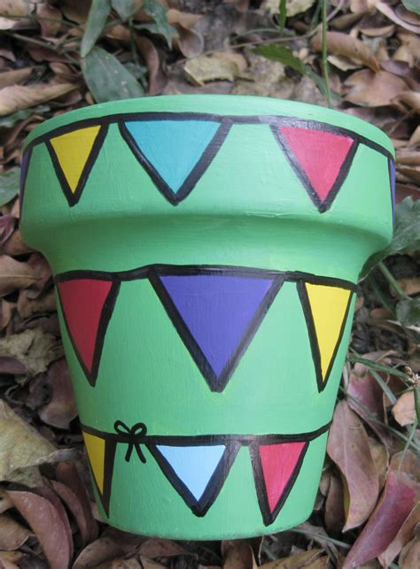 a painted pot sitting on the ground with leaves around it and plants in ...