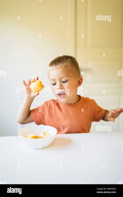 Cute boy having apple on dining table at home Stock Photo - Alamy