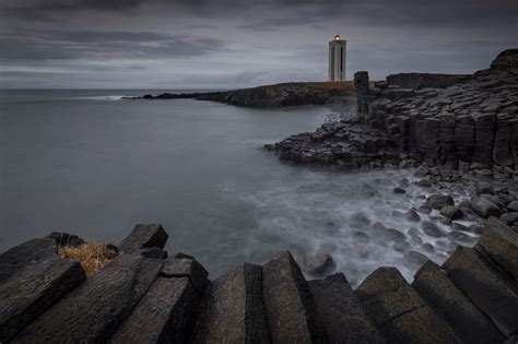 Light in the Dark - A gloomy, mysterious sunset over the basalt columns and famous lighthouse of ...