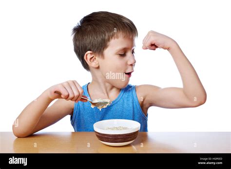 Happy boy eating porridge at the table isolated white Stock Photo - Alamy