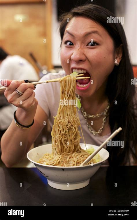 Young Asian girl eating Chinese noodle dish at a restaurant in Chinatown Manhattan, New York, NY ...