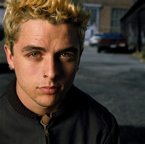 a man with blonde hair wearing a black jacket and looking at the camera ...