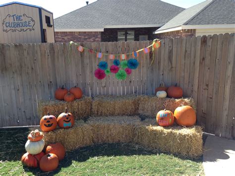 hay bales with pumpkins and pom - poms on them in front of a fence