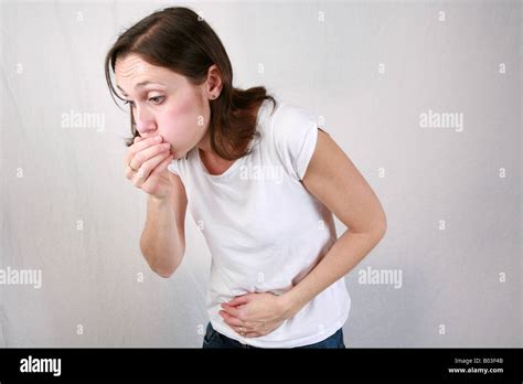 Young woman holds stomach and covers mouth while retching before vomiting being violently sick ...