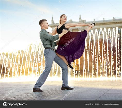 Beautiful young couple practicing dance moves near fountain outdoors ...