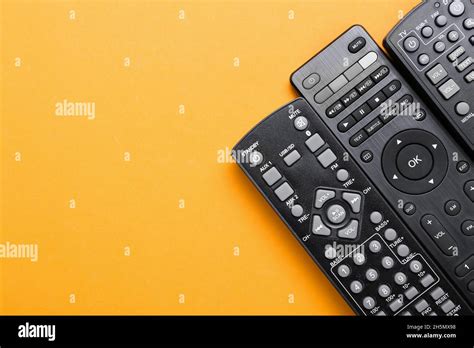 Different TV remote controllers on orange background Stock Photo - Alamy