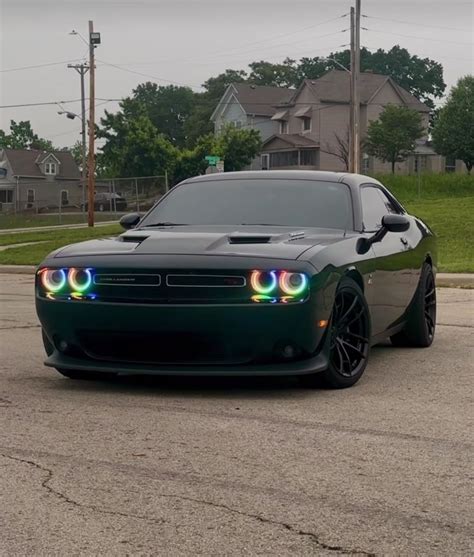 a black and white car parked on the side of a road with its lights on