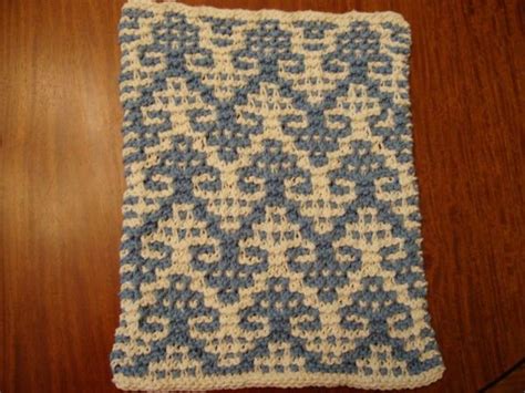 a blue and white crocheted dishcloth sitting on top of a wooden table